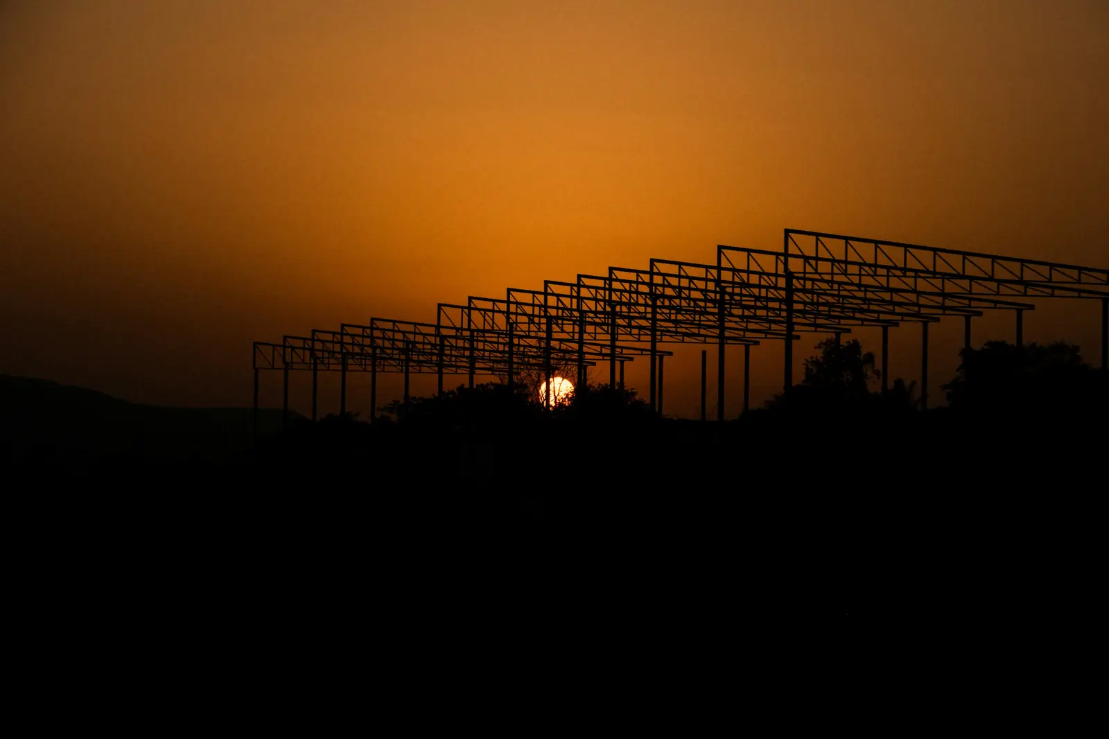Rows of steel mounting frames silhouetted against a sunset sky