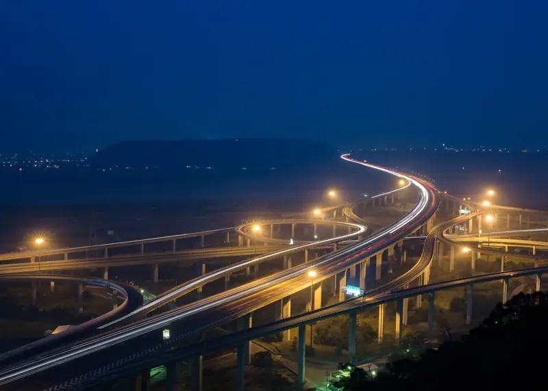 Multi-level road interchange at dusk with vehicle light trails