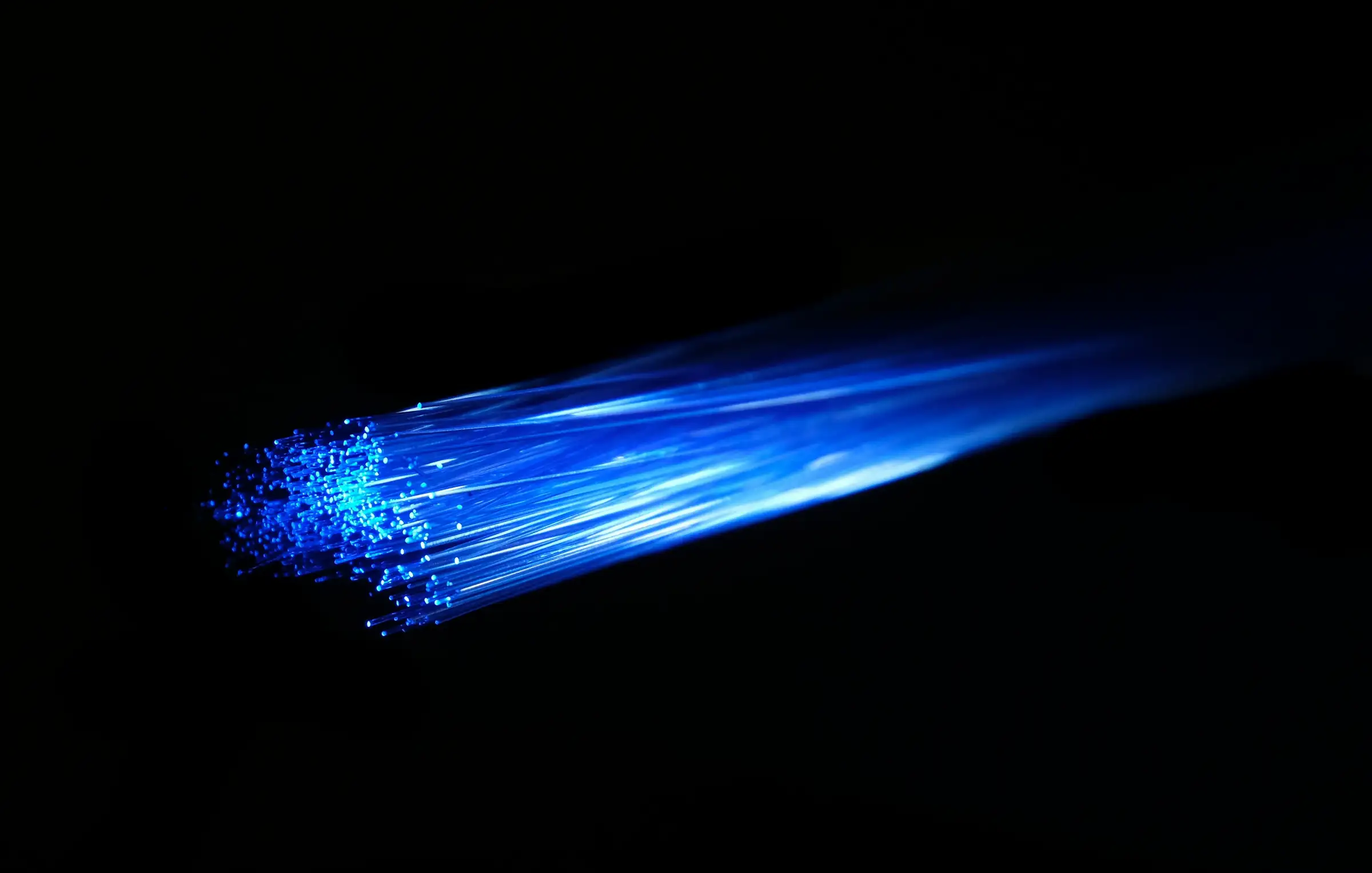 Optical fibre strands glowing at their cut ends against black