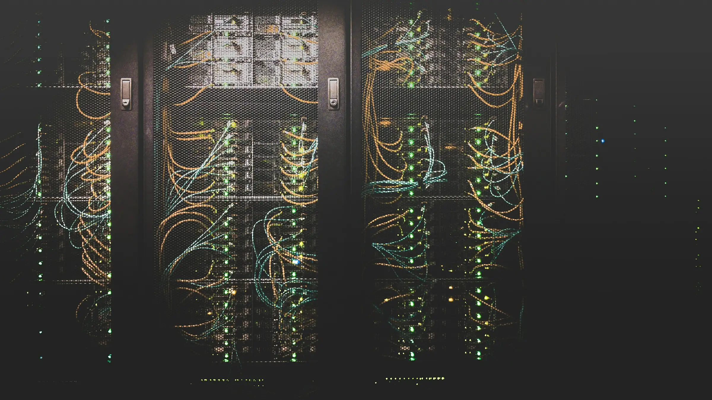 Equipment racks in a dark data hall, patch cables and status lights across the front panels